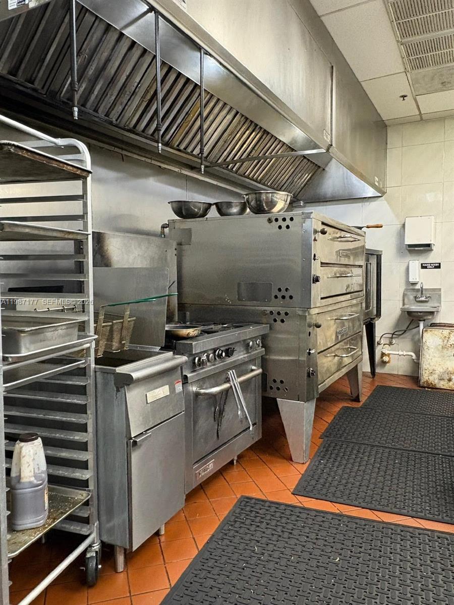 A commercial kitchen features stainless steel appliances, a large exhaust hood, and tiled flooring — Main Road, Weston FL 33327, WESTON, FL