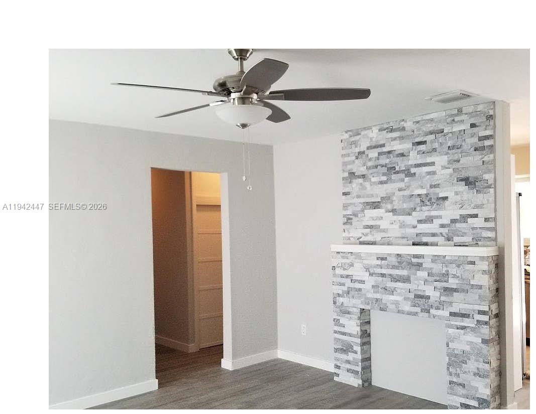 A room features a stone-tiled fireplace, gray wood-look flooring, and a ceiling fan — 2917 NW 9th Ave, Wilton Manors FL 33311, WILTON MANORS, FL