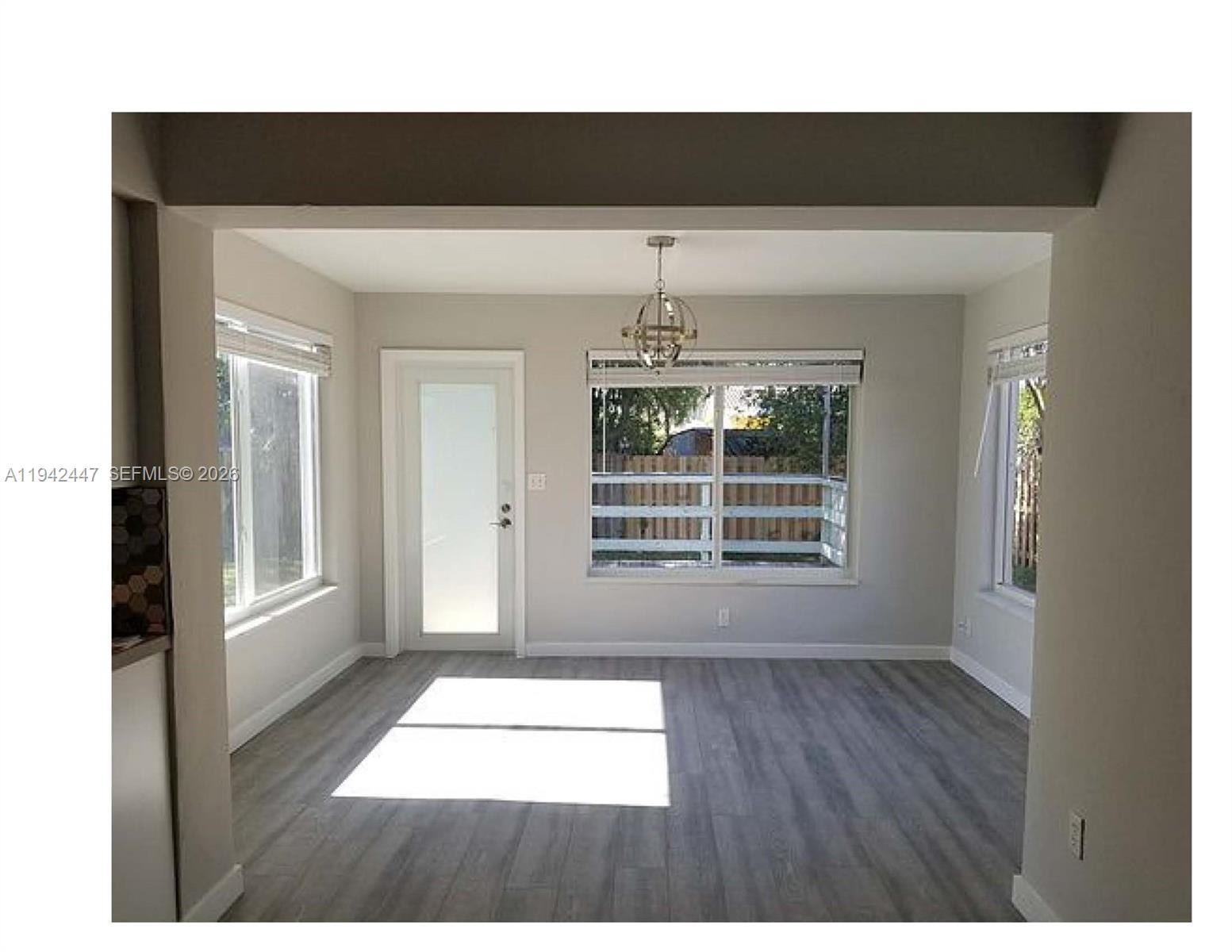 A dining area features gray wood-look flooring, a glass-paneled door, and a modern chandelier — 2917 NW 9th Ave, Wilton Manors FL 33311, WILTON MANORS, FL