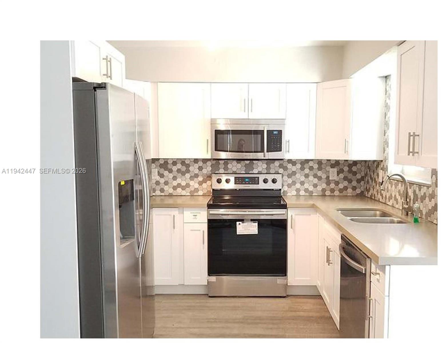 A kitchen features white cabinets, stainless steel appliances, and a gray hexagonal tile backsplash — 2917 NW 9th Ave, Wilton Manors FL 33311, WILTON MANORS, FL
