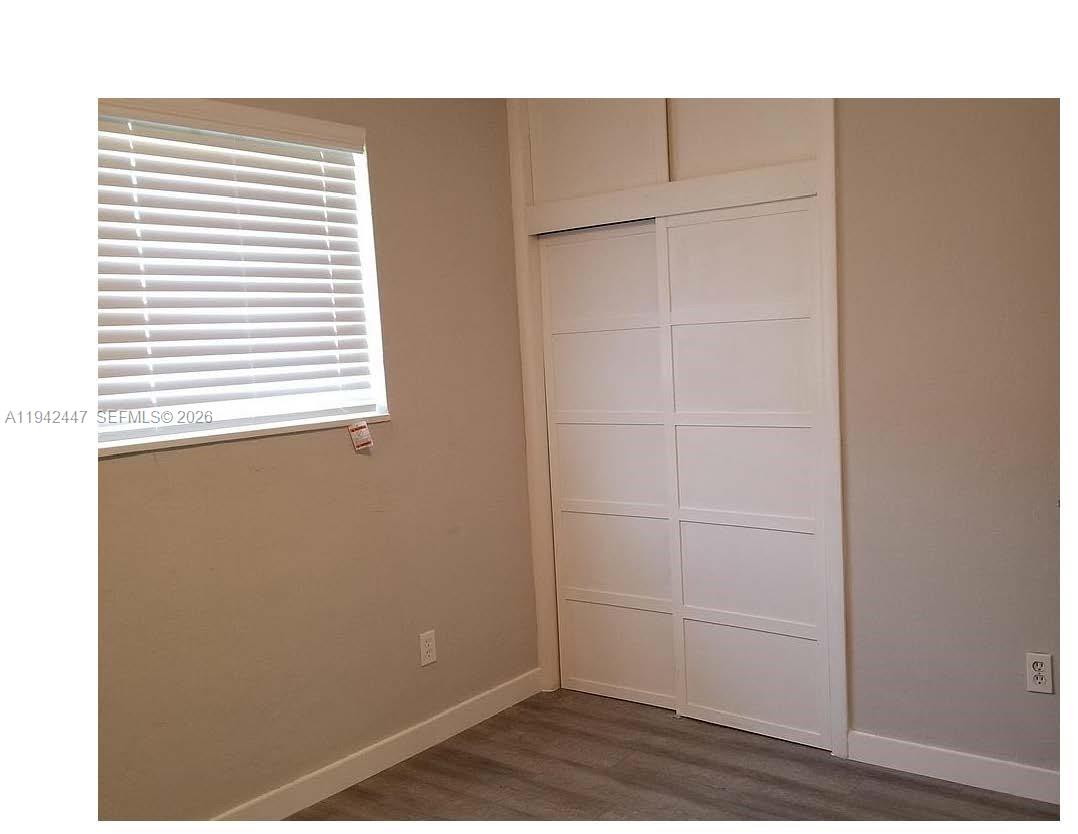 A bedroom features a window with white blinds, light-colored walls, and a white sliding-door closet — 2917 NW 9th Ave, Wilton Manors FL 33311, WILTON MANORS, FL