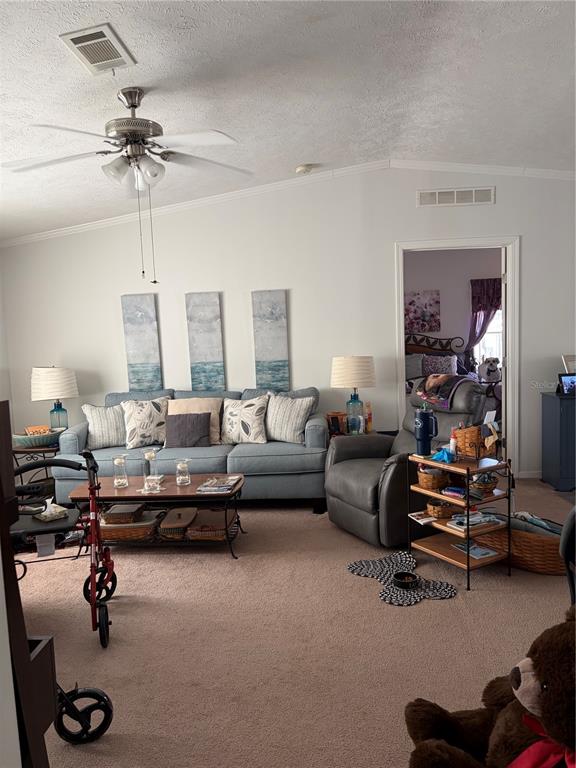 A living room features a blue sofa, a gray recliner, and a ceiling fan — 212 YORK COTTAGE DRIVE, HAINES CITY, FL