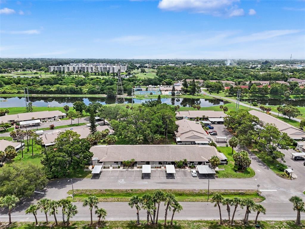 An aerial view shows a residential complex with multiple buildings, parking carports, and a lake — 1208 HIGHLAND AVENUE SE UNIT 121, LARGO, FL