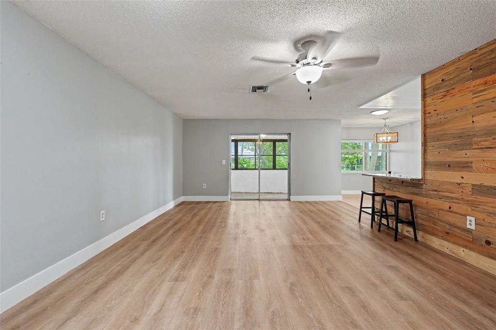 An open living area features light wood-look flooring, gray walls, and a wood-paneled breakfast bar — 1208 HIGHLAND AVENUE SE UNIT 121, LARGO, FL