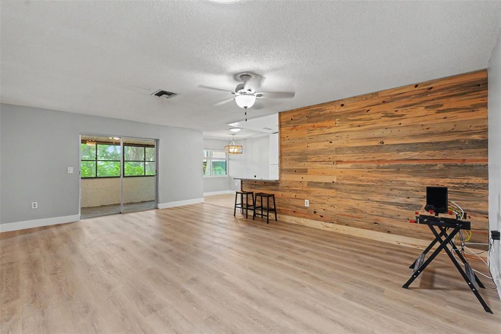 A living room features light wood-look flooring, a wood-plank accent wall, and a ceiling fan — 1208 HIGHLAND AVENUE SE UNIT 121, LARGO, FL