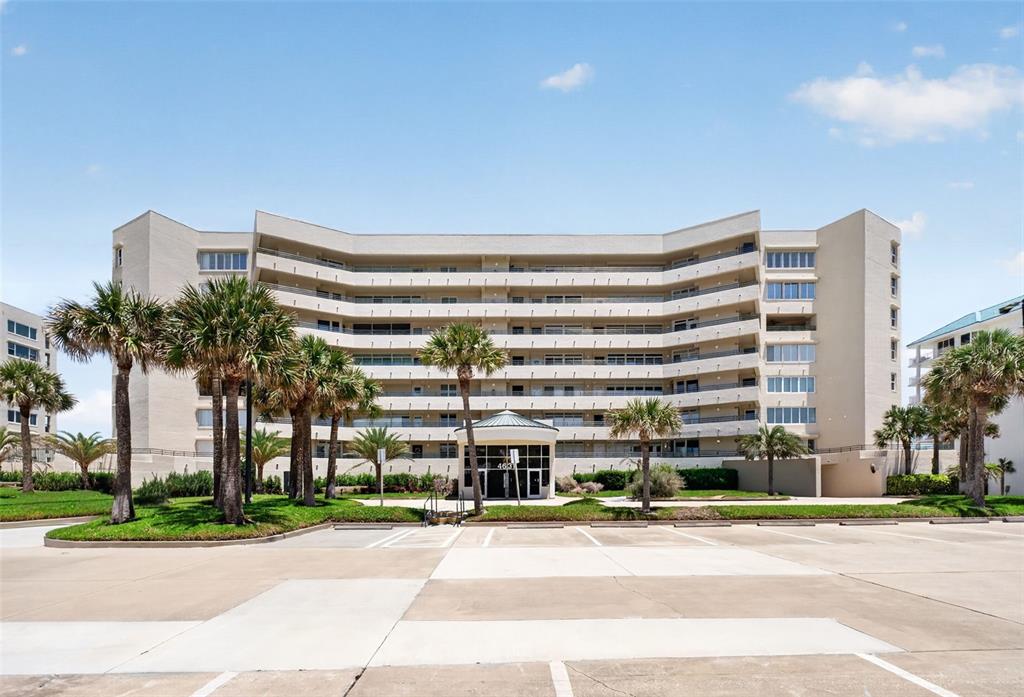 A multi-story beige apartment building with balconies and palm trees in front — 4631 S ATLANTIC AVENUE UNIT 8202, PORT ORANGE, FL