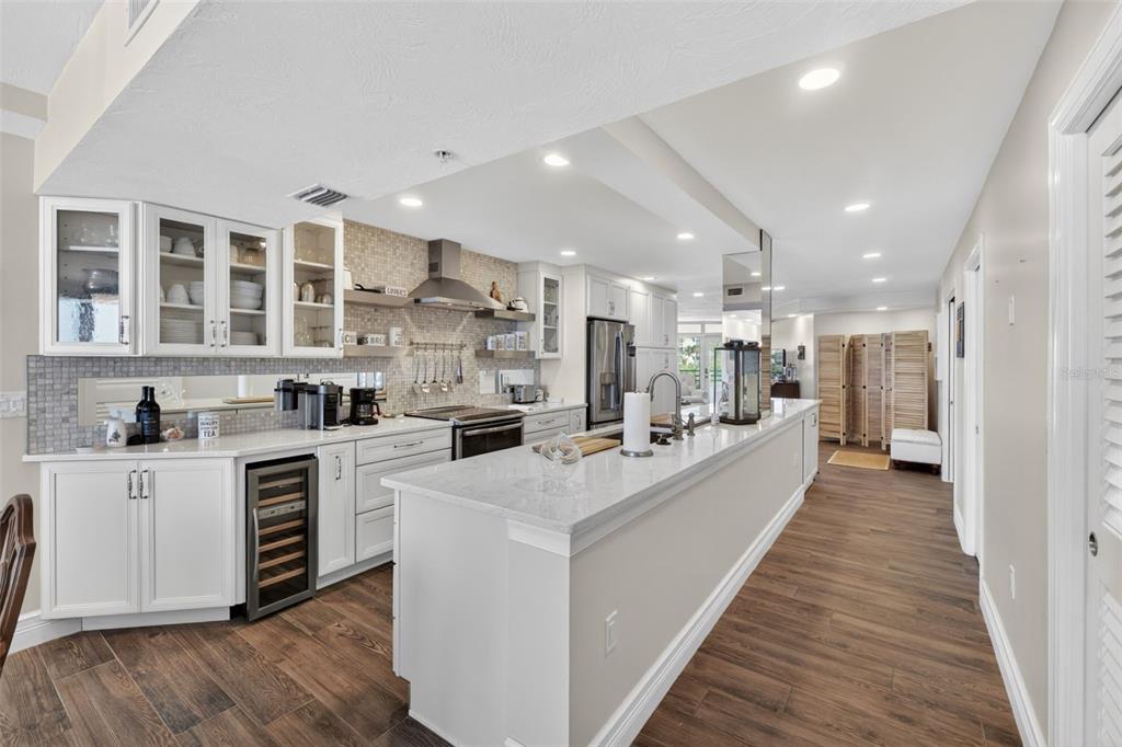 A modern kitchen features white cabinetry, a long quartz island, and wood-look flooring — 4631 S ATLANTIC AVENUE UNIT 8202, PORT ORANGE, FL