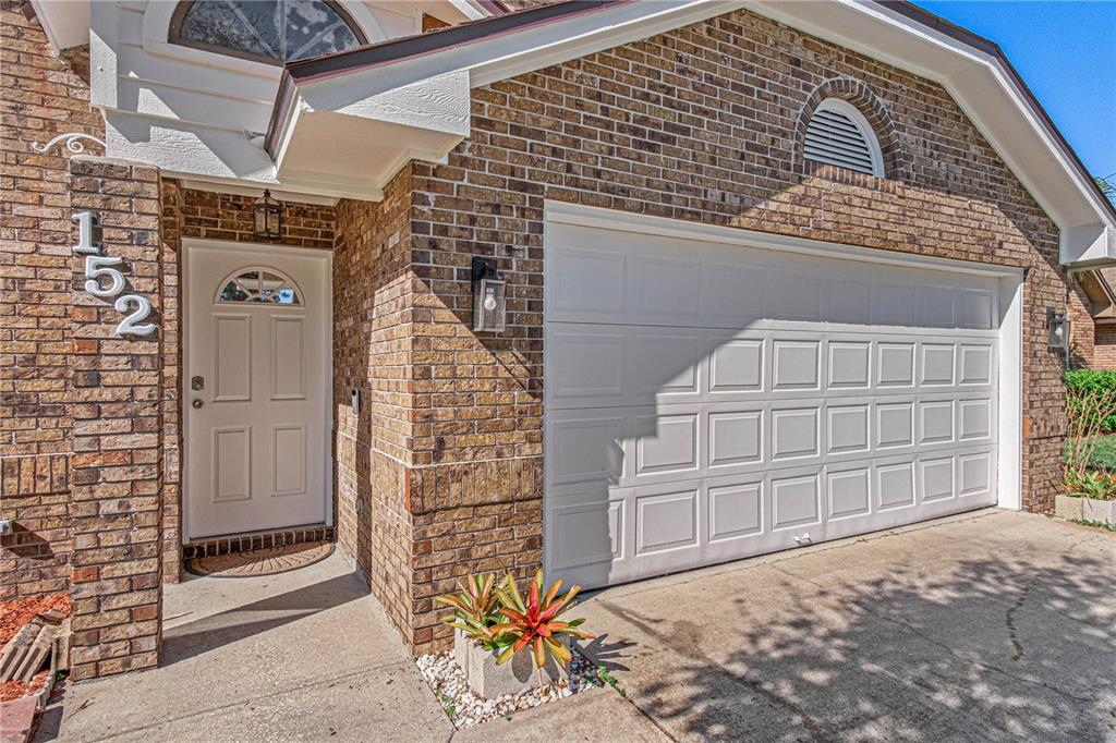 A brick house exterior features a white front door, a garage, and a small planter — 152 LOON COURT, DAYTONA BEACH, FL