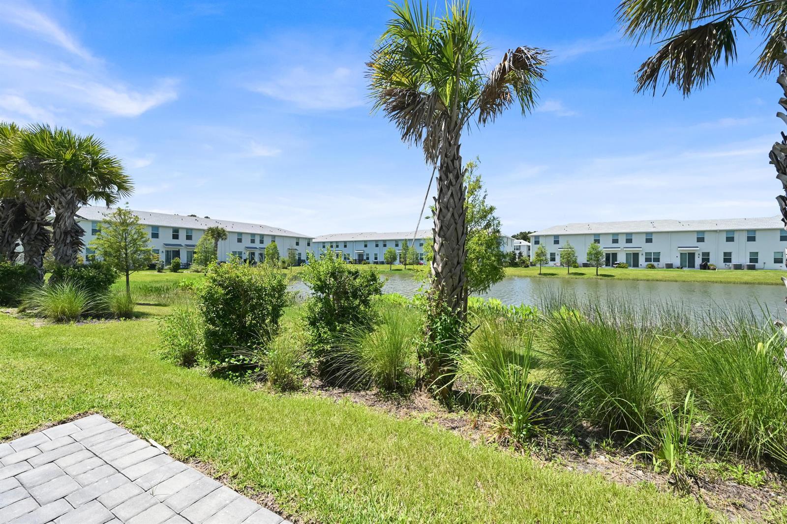 A view of a pond surrounded by green grass, landscaping, and multi-story residential buildings — 575 Salisbury Circle, Fort Pierce FL 34982, FORT PIERCE, FL