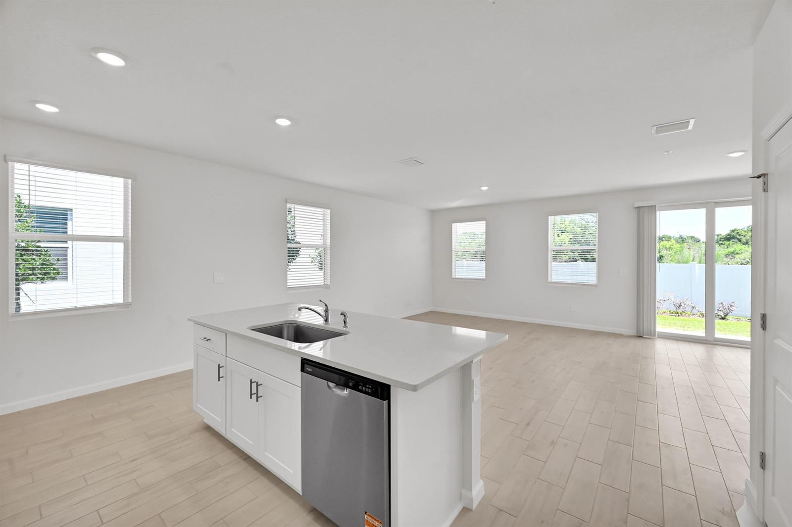 A kitchen island with a stainless steel dishwasher sits in an open-concept room with tile floors — 575 Salisbury Circle, Fort Pierce FL 34982, FORT PIERCE, FL
