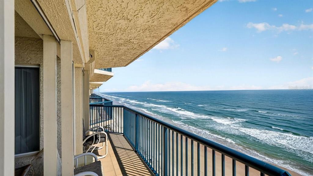 A high-rise balcony overlooks the ocean with a blue metal railing and outdoor seating — 3425 S ATLANTIC AVENUE UNIT 1706, DAYTONA BEACH, FL