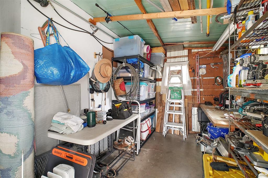 A cluttered storage shed features metal shelving units, a folding table, and various tools and supplies — 11723 MAGNOLIA AVENUE, TAVARES, FL