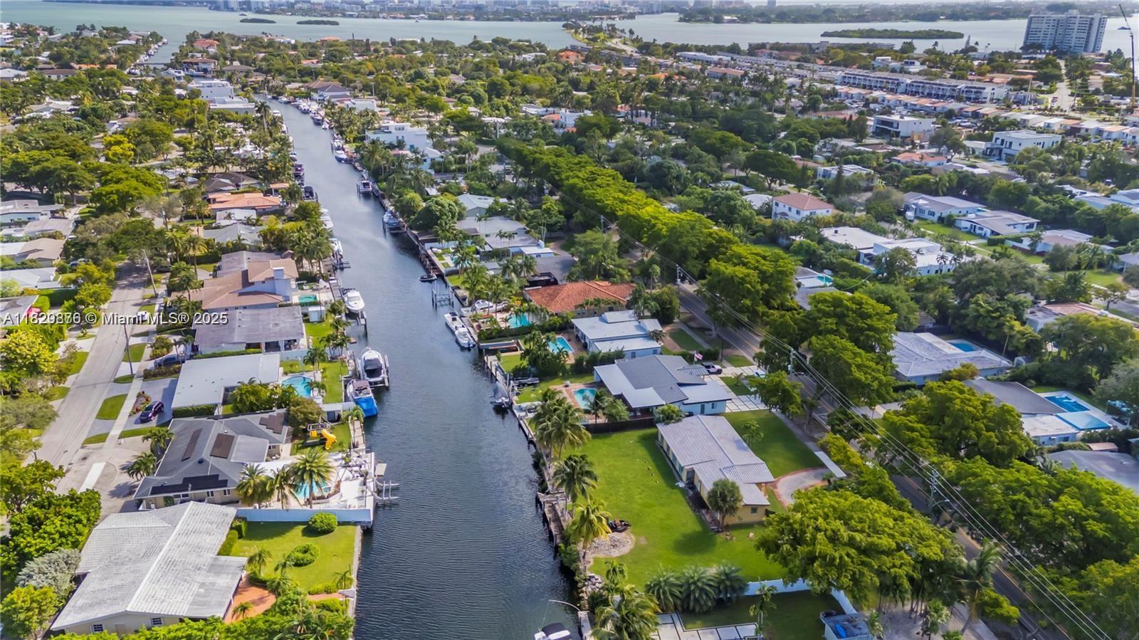 An aerial view shows a canal lined with houses, swimming pools, and docked boats — 1865 Keystone Blvd, North Miami FL 33181, NORTH MIAMI, FL