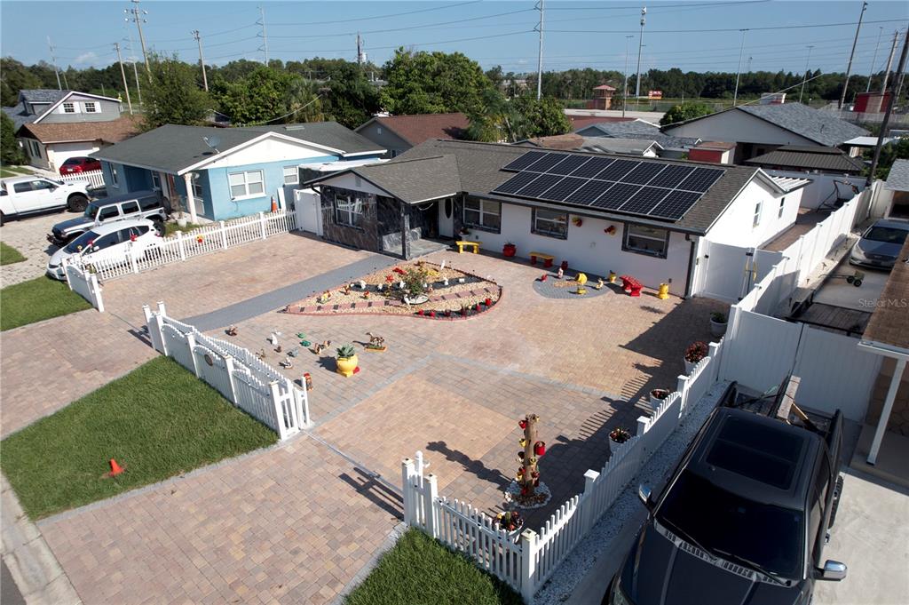 An aerial view of a single-story house with solar panels, a paved courtyard, and fencing — 4527 W ELM STREET, TAMPA, FL
