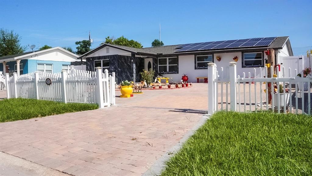 A single-story house with solar panels, a paved driveway, and a white picket fence — 4527 W ELM STREET, TAMPA, FL