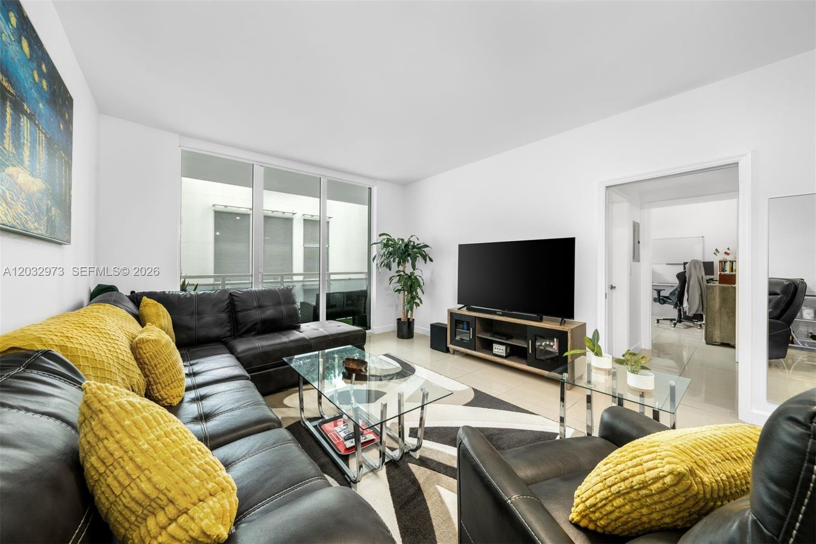 A living room features a black leather sectional, glass coffee tables, and a large television — 950 Brickell Bay Dr # 803, Miami FL 33131, MIAMI, FL