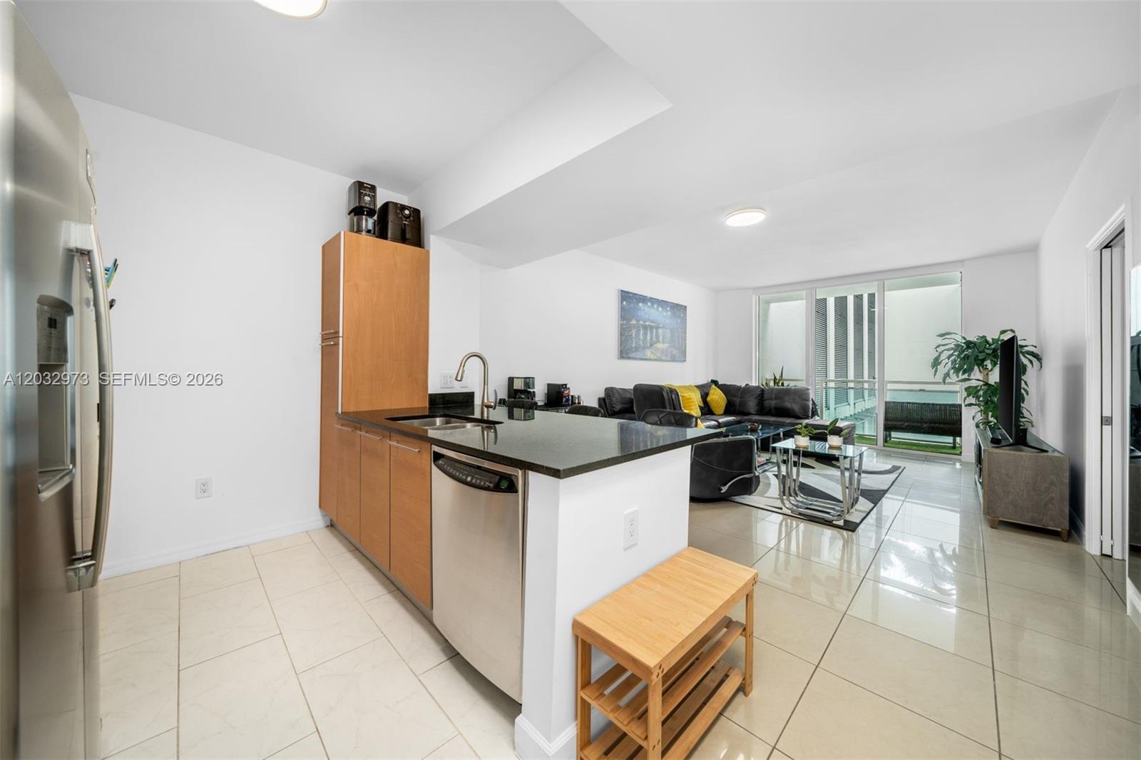 A kitchen with stainless steel appliances and dark countertops opens into a living area — 950 Brickell Bay Dr # 803, Miami FL 33131, MIAMI, FL