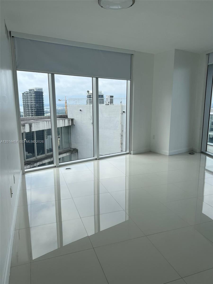 A bright, empty room features white tile flooring, floor-to-ceiling windows, and city views — 475 Brickell Ave # 5508, Miami FL 33131, MIAMI, FL