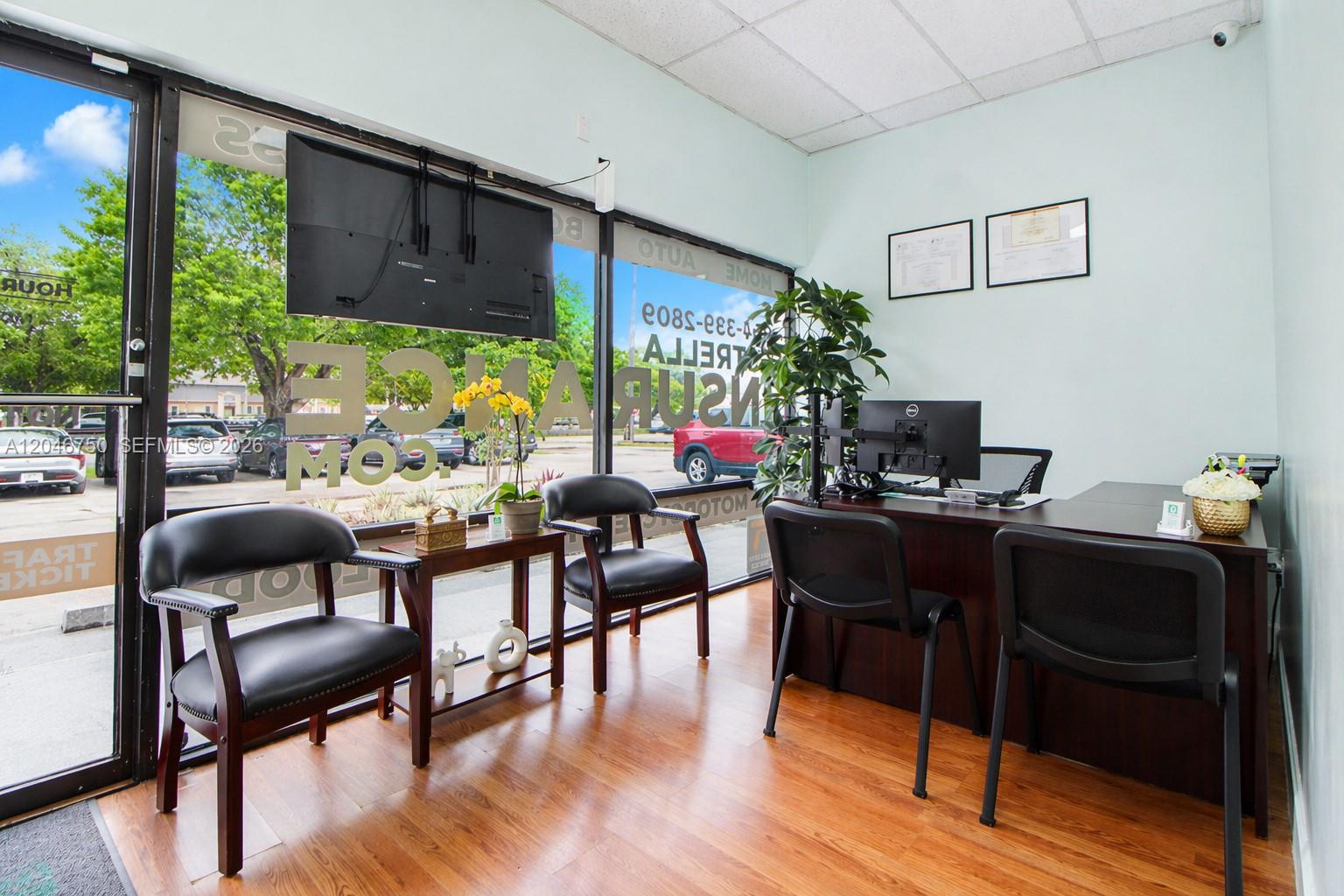 This office space features a desk, two guest chairs, a television, and large glass windows — HALLANDALE BEACH, FL