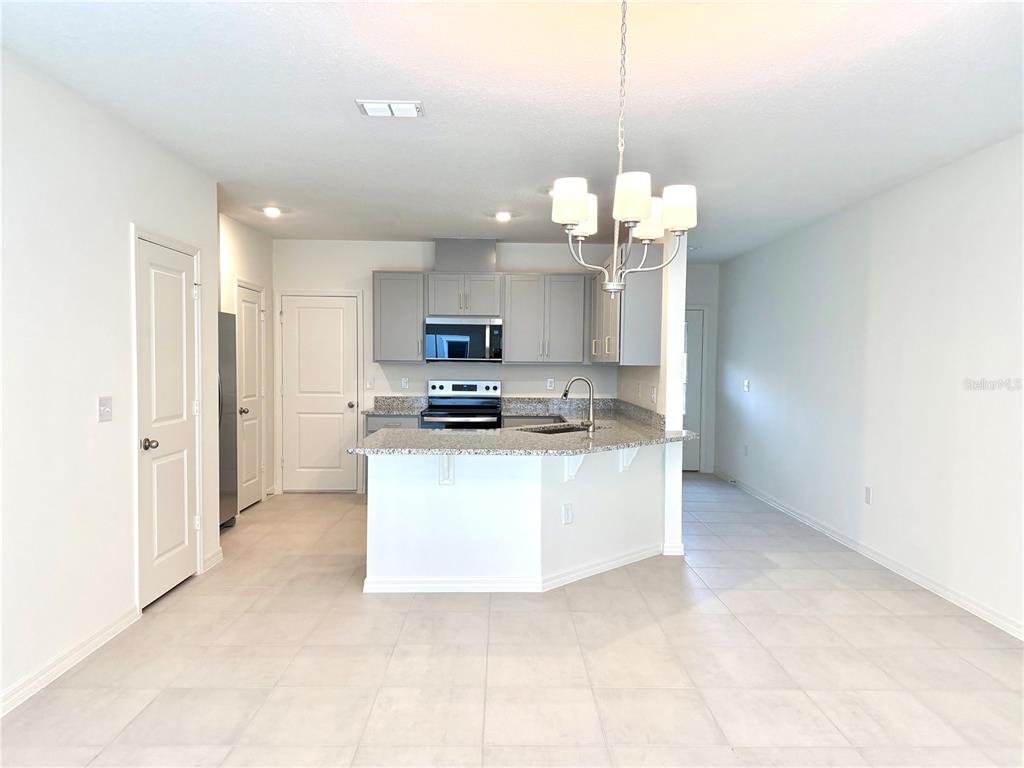A kitchen with gray cabinets, granite countertops, and a breakfast bar island — 2817 MOONSHADOW COURT, CLERMONT, FL