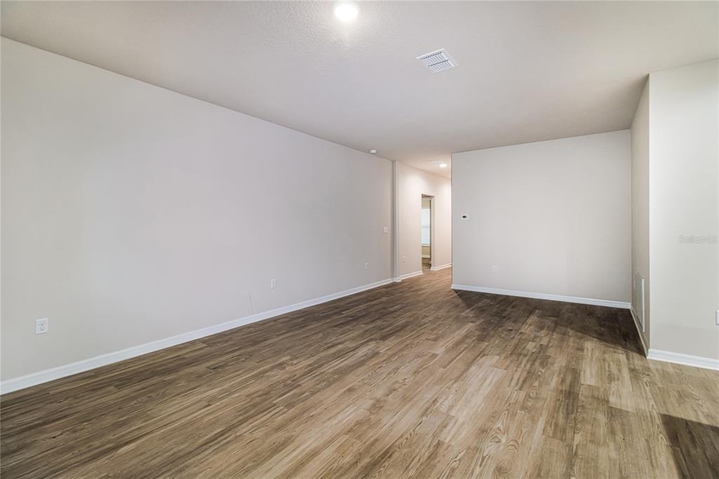 An empty room with light-colored walls, wood-look flooring, and a doorway leading to a hallway — 2087 W SHINING DAWN LANE, LECANTO, FL