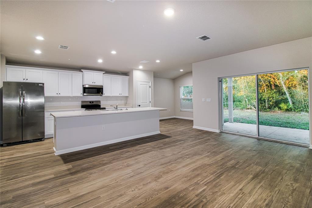 A kitchen with white cabinets, stainless steel appliances, and an island overlooks a backyard patio — 2087 W SHINING DAWN LANE, LECANTO, FL