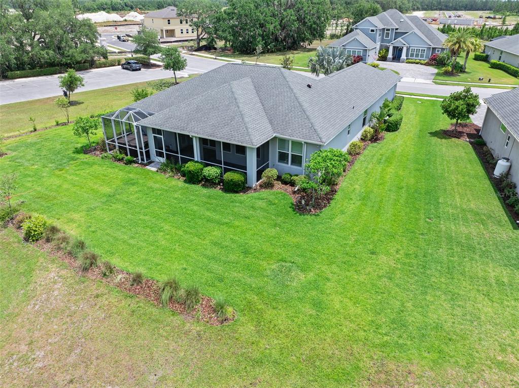 An aerial view shows the back of a house with a screened-in patio and lawn — 3322 MODENA WAY, NEW SMYRNA BEACH, FL