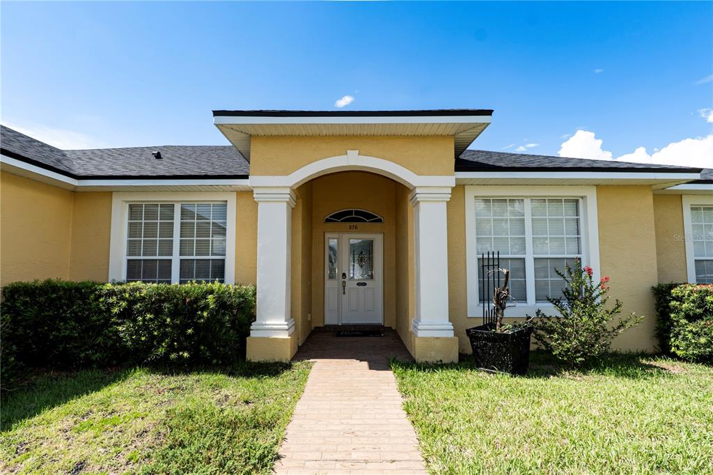 The exterior of a yellow house features a covered entryway with white columns — 276 TERRANOVA BOULEVARD, WINTER HAVEN, FL