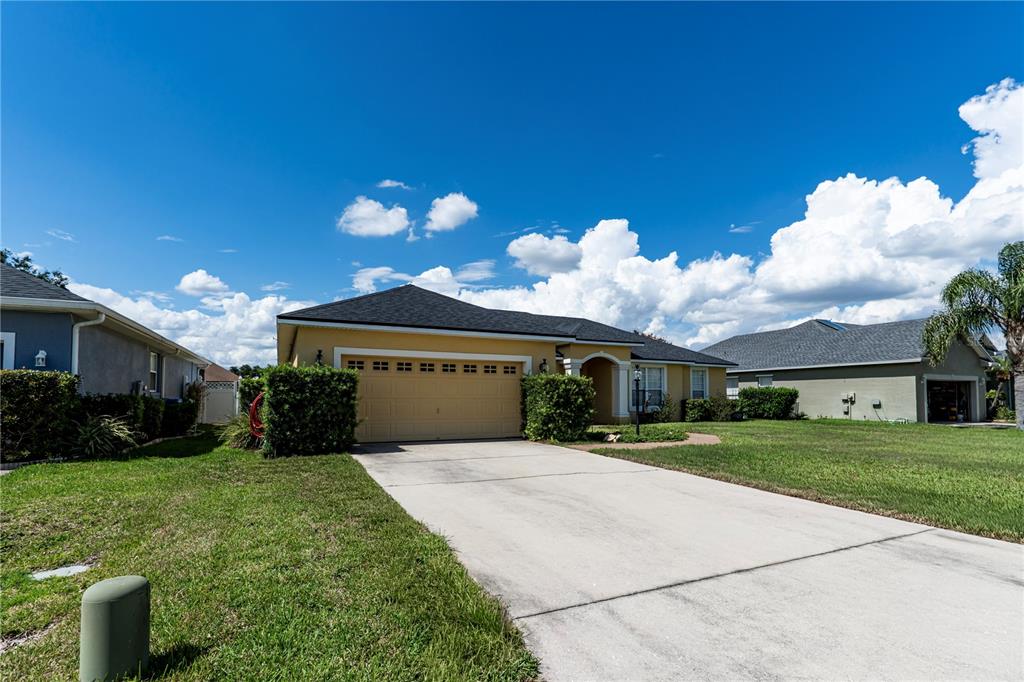 A yellow single-story house with a two-car garage and a concrete driveway — 276 TERRANOVA BOULEVARD, WINTER HAVEN, FL