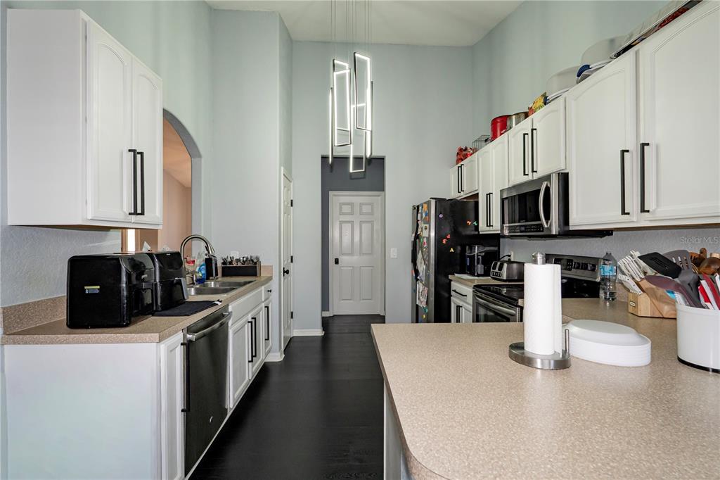 A kitchen features white cabinets, dark flooring, a central island, and a modern pendant light — 276 TERRANOVA BOULEVARD, WINTER HAVEN, FL