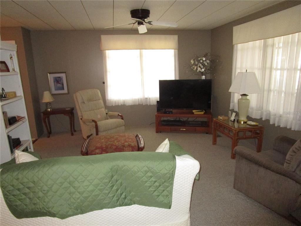 A kitchen with white cabinets, a white stove, and a dining area with wicker chairs — 47 KONO CIRCLE, LEESBURG, FL