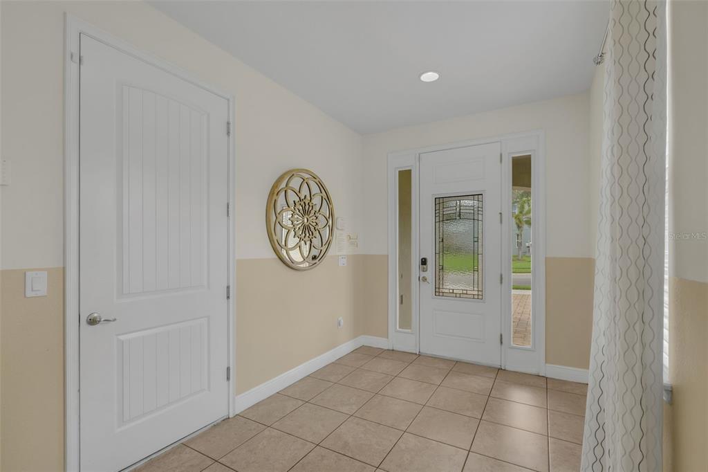 A tiled entryway features a white front door with sidelights and a decorative wall ornament — 7541 MARKER AVENUE, KISSIMMEE, FL