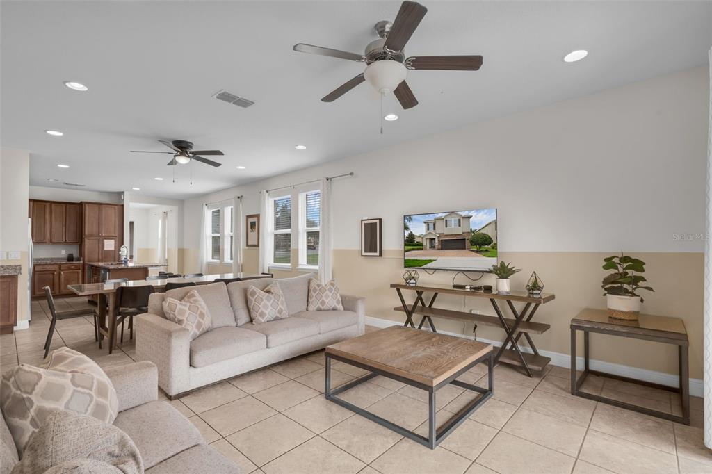 A living room features tile flooring, a beige sofa, a coffee table, and a ceiling fan — 7541 MARKER AVENUE, KISSIMMEE, FL