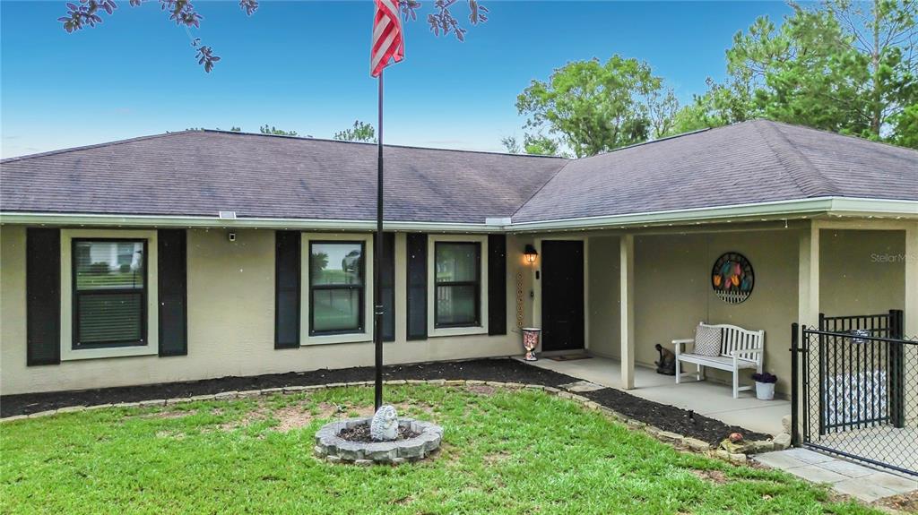 A single-story house with a flag pole, covered porch, and black shutters — 1 REDWOOD RUN COURT, OCALA, FL