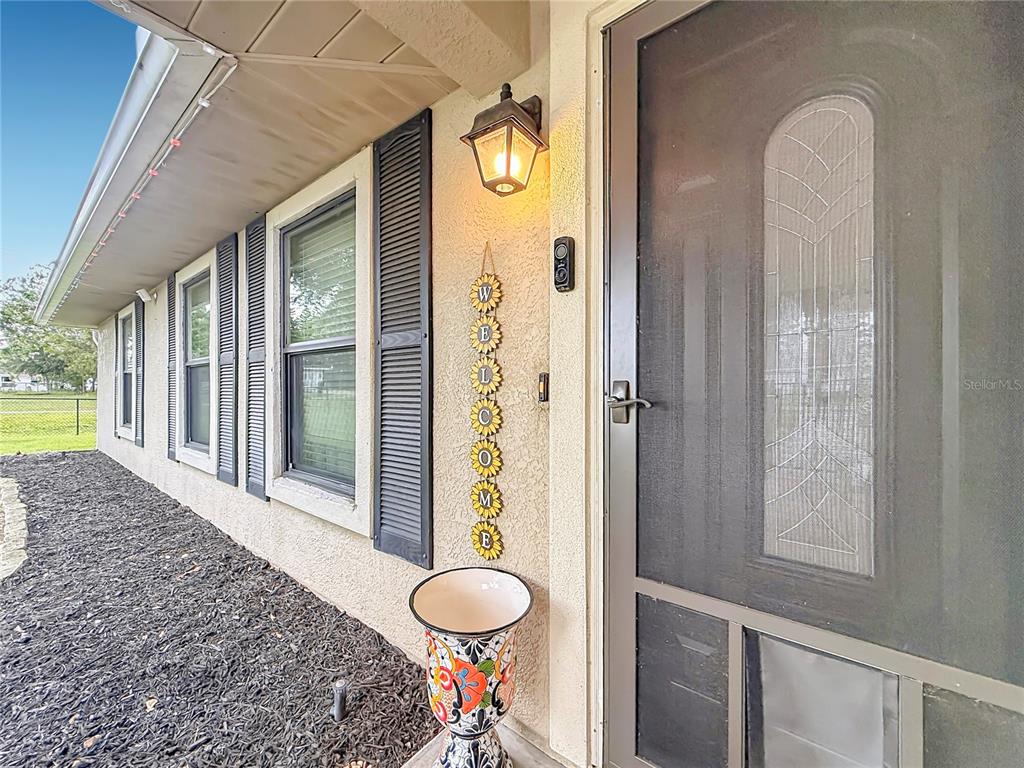 A front entryway features a screen door, a sunflower welcome sign, and a decorative planter — 1 REDWOOD RUN COURT, OCALA, FL