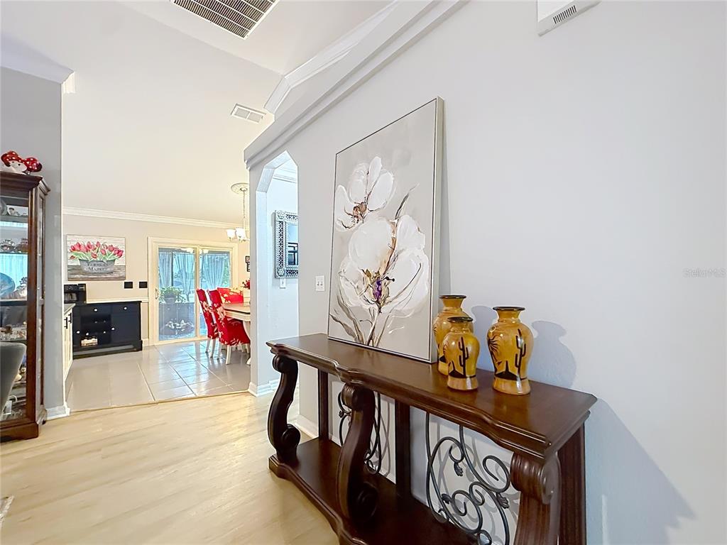 A wooden console table with vases sits in a hallway leading to a dining area — 1 REDWOOD RUN COURT, OCALA, FL
