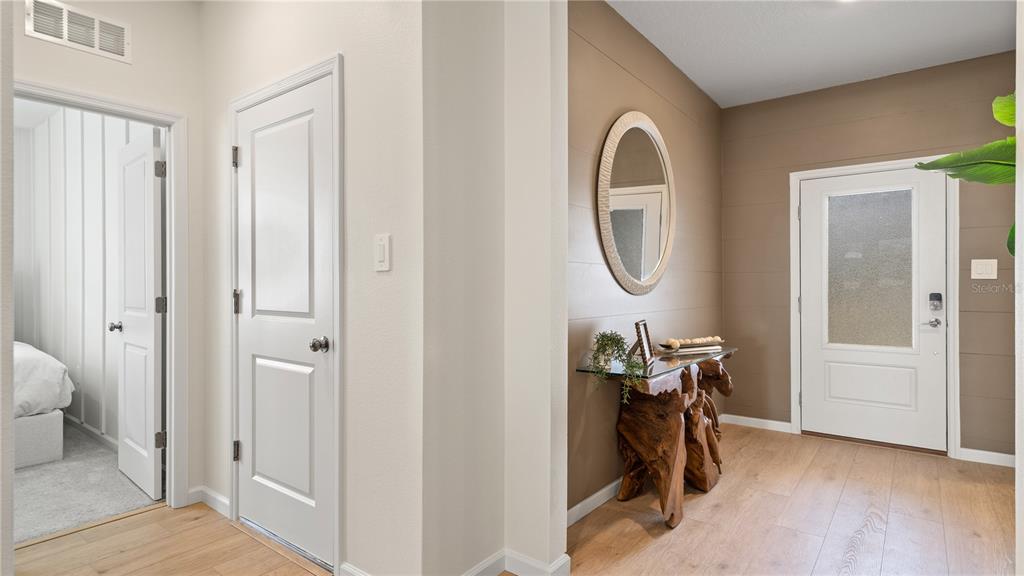 An entryway features a wood-plank accent wall, a rustic console table, and a white door — 4946 WALTHAM FOREST DRIVE, DAVENPORT, FL