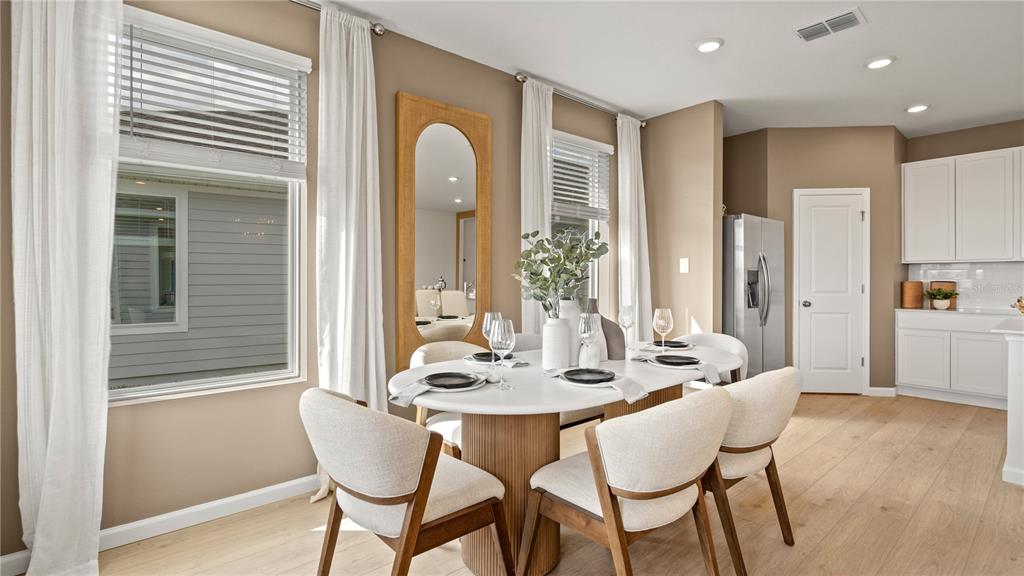 A dining room features a white oval table, four chairs, and a large arched mirror — 4946 WALTHAM FOREST DRIVE, DAVENPORT, FL