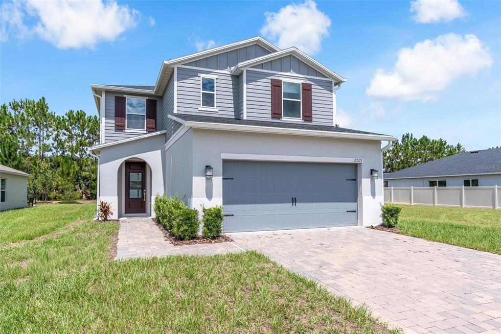 A two-story house with a gray garage, light-colored stucco, and a paved driveway — 2729 SANCTUARY DRIVE, CLERMONT, FL