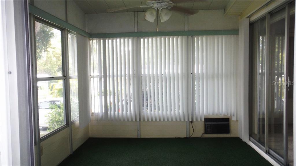 A sunroom features green carpeting, vertical blinds, a ceiling fan, and a wall-mounted air conditioner — 37 HONEY BEAR COURT UNIT 54, SAFETY HARBOR, FL