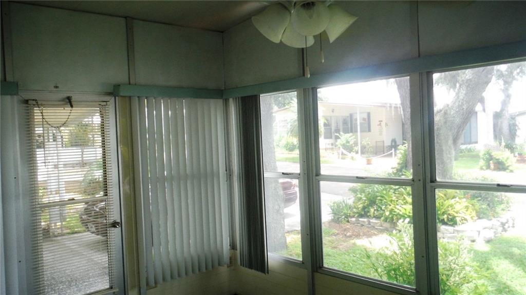 A sunroom with large windows, vertical blinds, a glass-paneled door, and a ceiling light fixture — 37 HONEY BEAR COURT UNIT 54, SAFETY HARBOR, FL