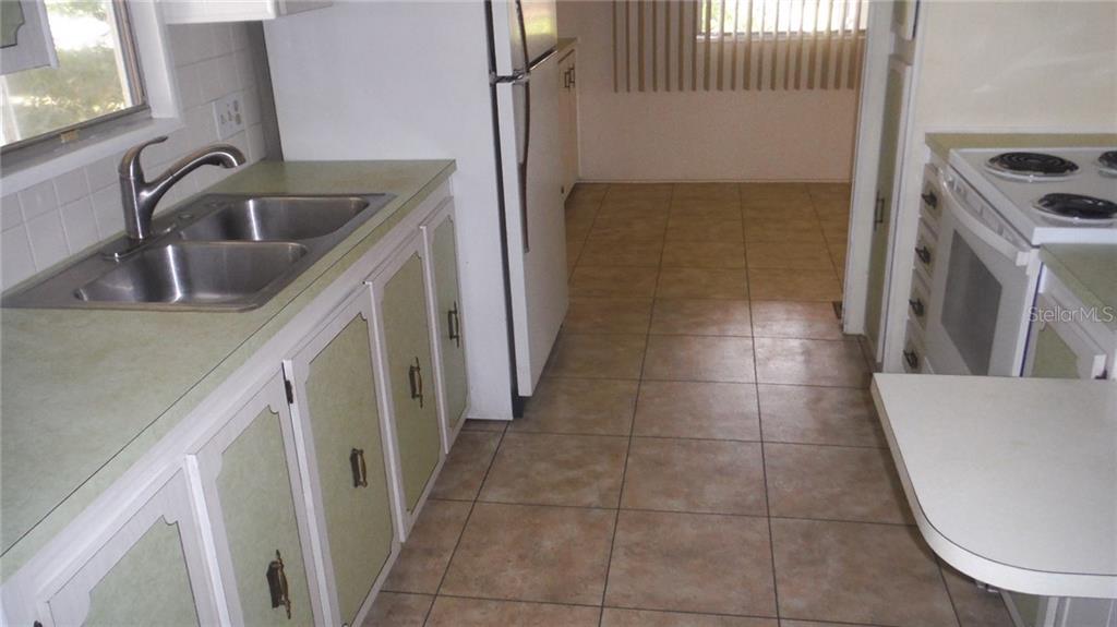 A room with beige walls, carpeted flooring, a ceiling fan, sliding glass doors, and blinds — 37 HONEY BEAR COURT UNIT 54, SAFETY HARBOR, FL