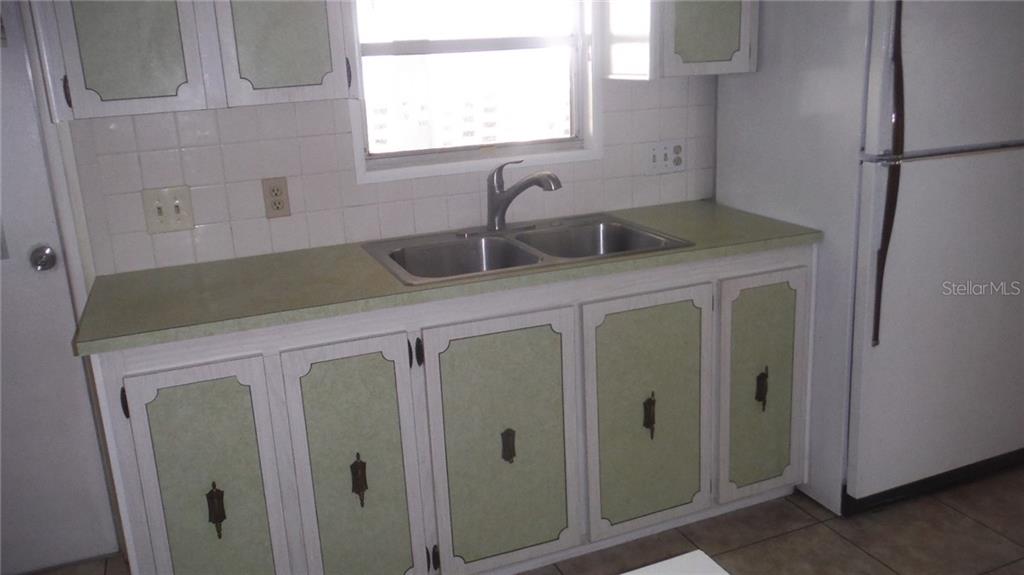 A kitchen features light green cabinets, a double sink, white appliances, and tiled flooring — 37 HONEY BEAR COURT UNIT 54, SAFETY HARBOR, FL