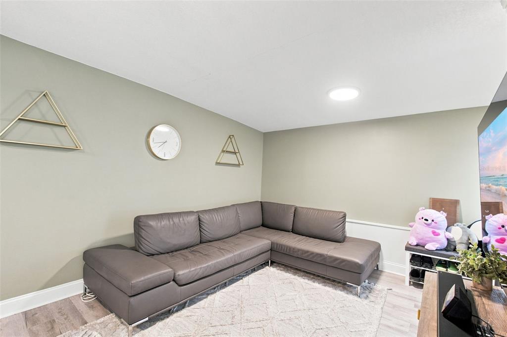 A living room features a grey sectional sofa, a white area rug, and wall decor — 1601 RENEE AVENUE, ORLANDO, FL
