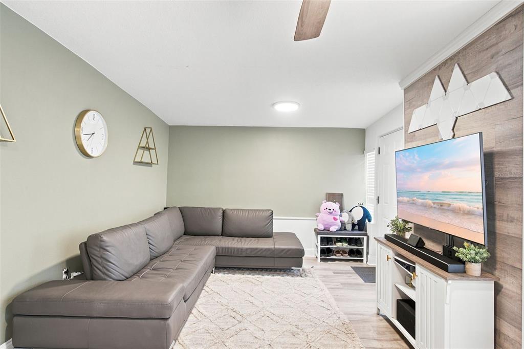 A living room features a grey sectional sofa, a television on a stand, and wall decor — 1601 RENEE AVENUE, ORLANDO, FL