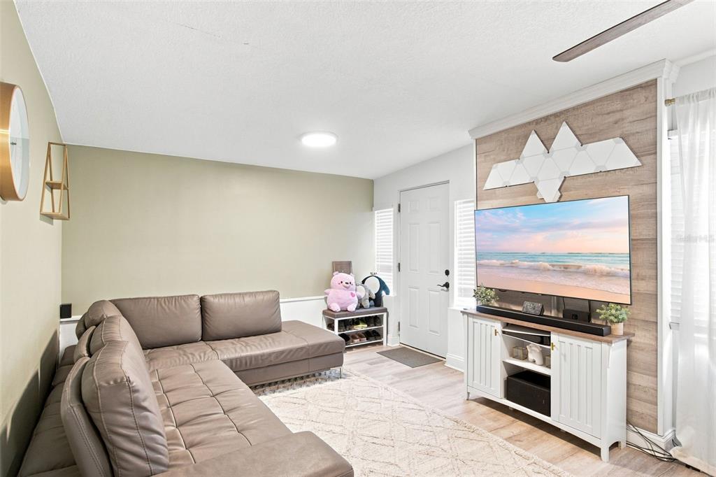 A living room features a grey sectional sofa, a wood-paneled accent wall, and a television — 1601 RENEE AVENUE, ORLANDO, FL