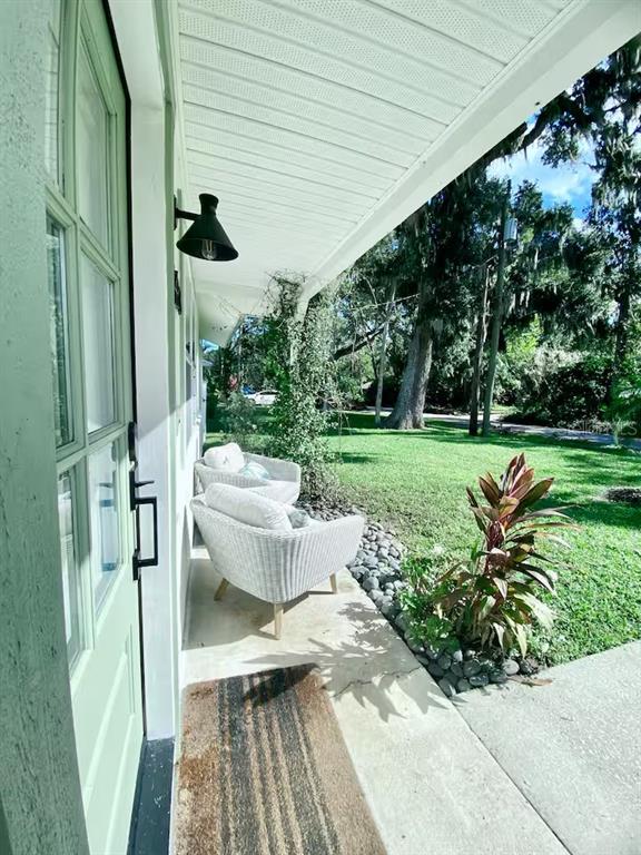 A covered porch features two white wicker chairs, a doormat, and a light fixture — 2433 LYDIA WAY, NEW SMYRNA BEACH, FL