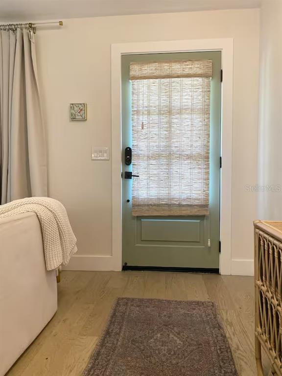A sage green door with a woven shade stands in a room with light wood floors — 2433 LYDIA WAY, NEW SMYRNA BEACH, FL