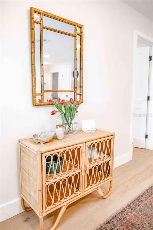 A rattan console table with a matching mirror sits against a white wall in a hallway — 2433 LYDIA WAY, NEW SMYRNA BEACH, FL