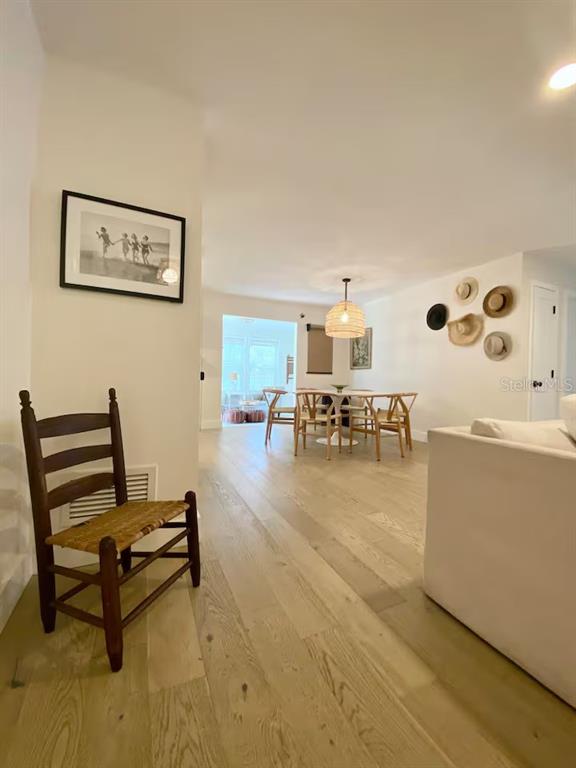 A wooden chair sits in the foreground of a bright dining area with light wood floors — 2433 LYDIA WAY, NEW SMYRNA BEACH, FL